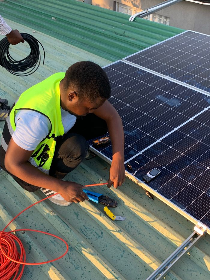 portfolio-02 Technician working on solar panel installation with cables and tools on a sunny day.