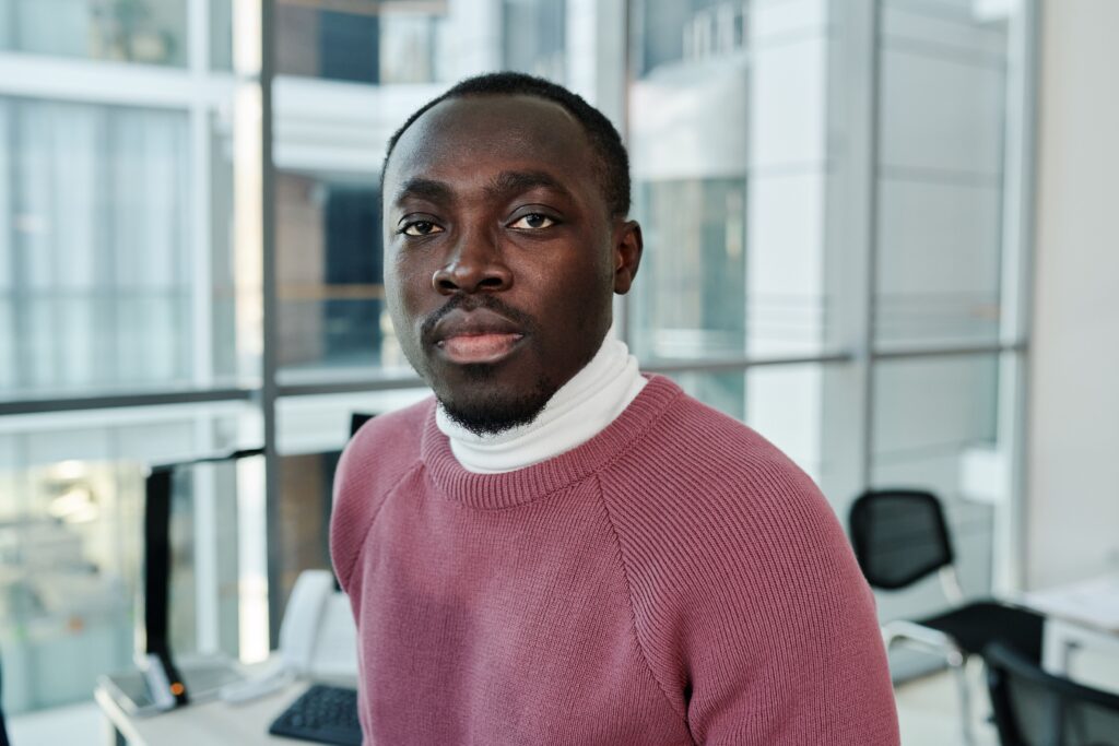 pexels photo 7109089 7109089 Portrait of a confident man in a cozy sweater in a bright, modern office environment.